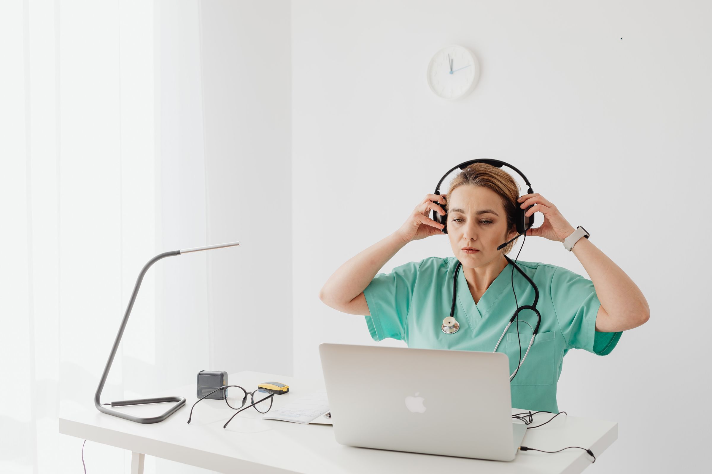 Infirmière fatiguée d'enchaîner les appels, mettant son casque devant son ordinateur